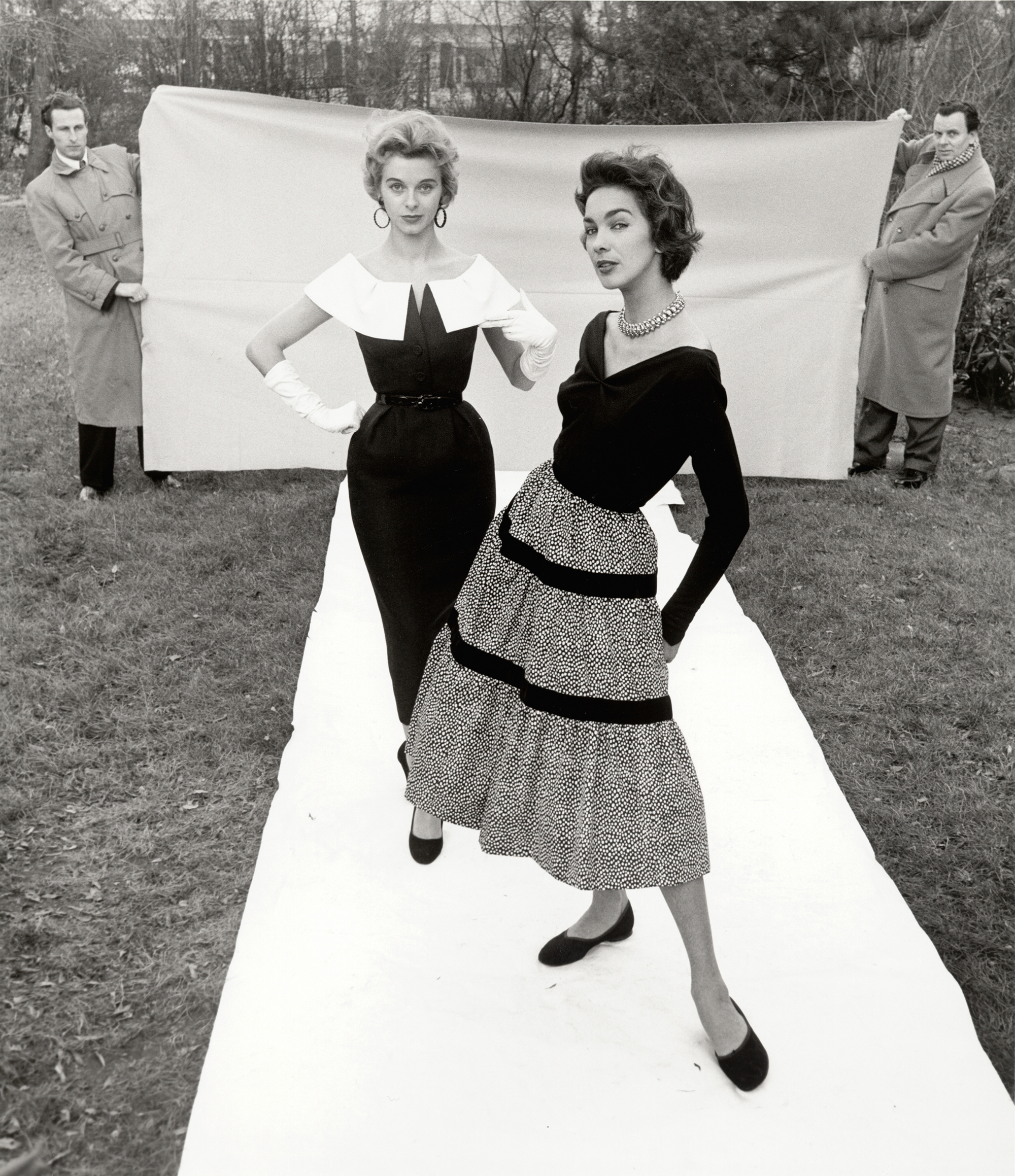 Fotografie: F.C. Gundlach, Candy Tannev und Elfi Wildfeuer, Chefredakteur Curt Waldenburger (“Film und Frau”) und sein Fahrer assistieren, Hamburg, 1954.